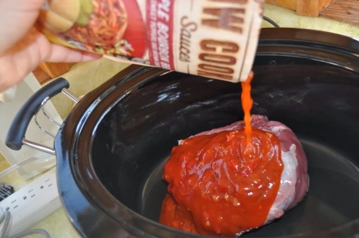 pouring the Campbell's Slow cooker sauce over the roast